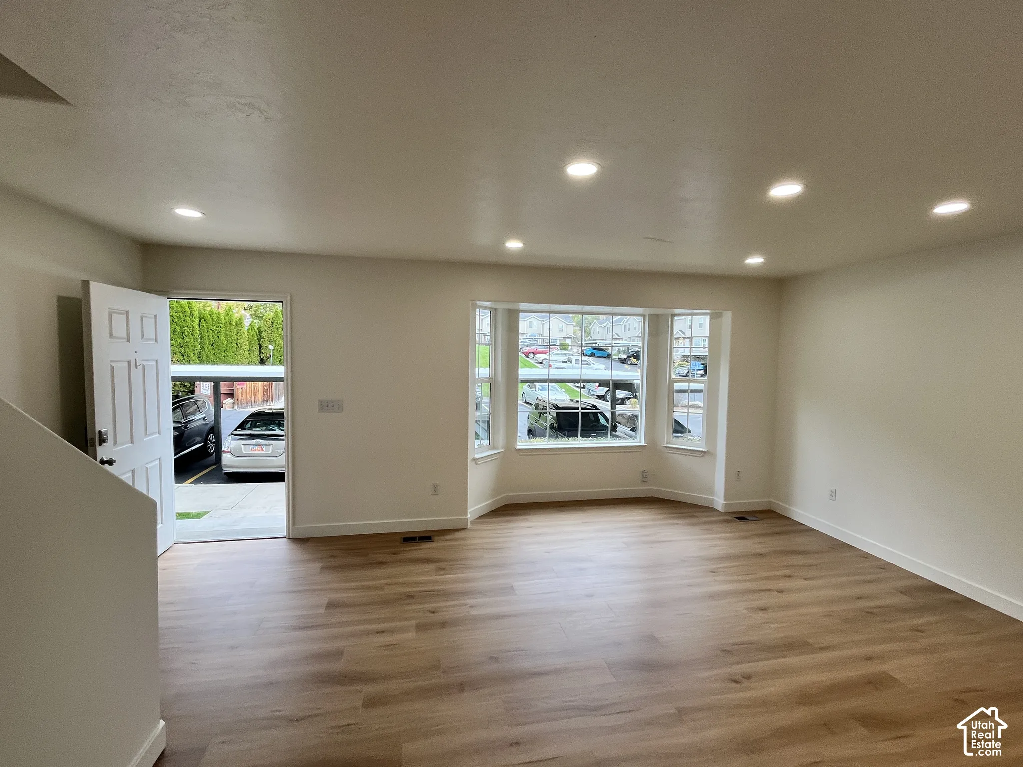 Open-concept interior featuring wood-finish flooring, recessed lighting, and a multi-pane bay window