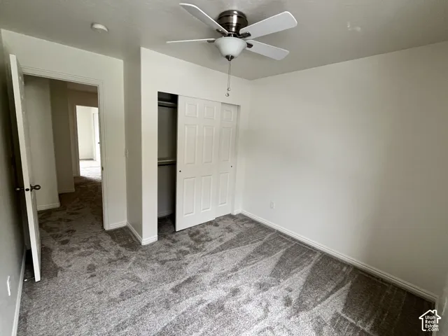 Neutral-toned wall-to-wall carpeting, ceiling fan with integrated lighting, and white six-panel closet doors