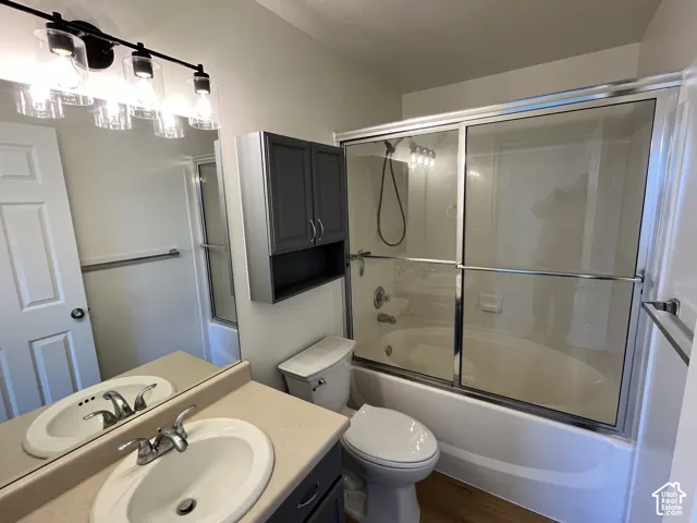 Bathroom featuring a vanity with a solid-surface countertop, an integrated sink, a wall-mounted medicine cabinet, a shower-tub combination with sliding glass doors, and a four-light fixture