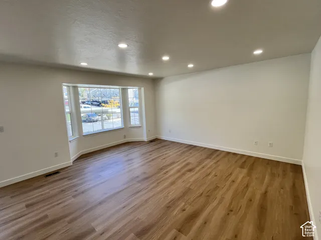 Interior space featuring wood-finish flooring, a multi-pane bay window, and recessed ceiling lighting