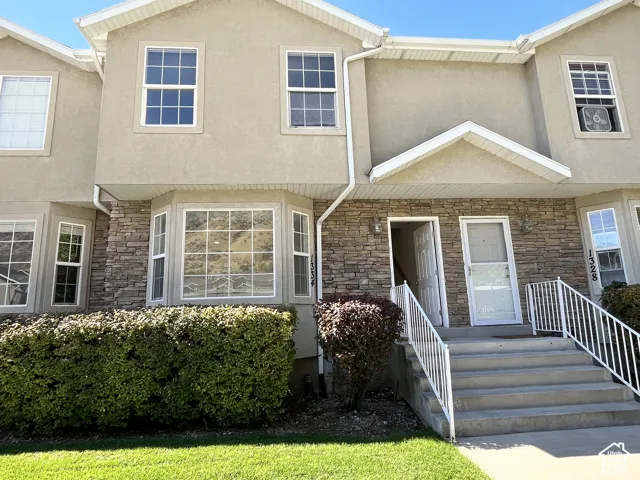 Multi-level exterior featuring stone veneer accents, stucco siding, a bay window, concrete steps, and white metal railings