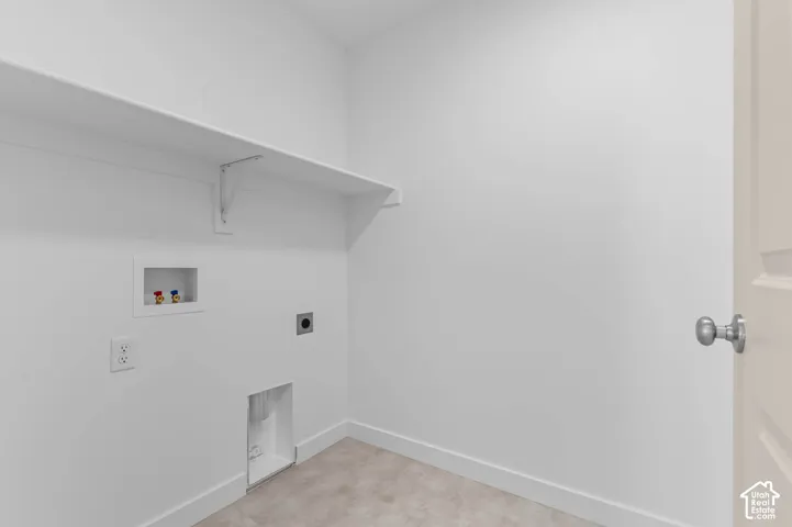 Dedicated utility space featuring neutral flooring, wall-mounted shelving, and integrated plumbing and electrical hookups