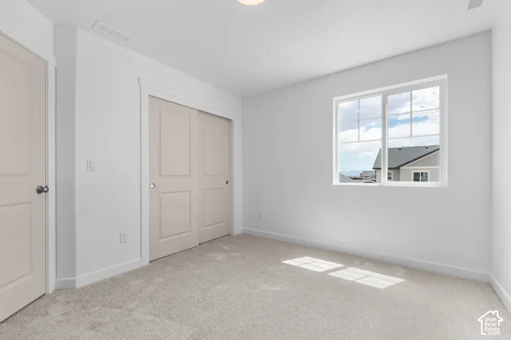 Neutral interior featuring wall-to-wall carpeting, a multi-panel sliding closet door, and a single-pane window with grid detailing
