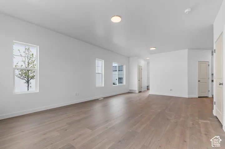 Interior space featuring wood-finish flooring, white walls, flush-mount ceiling lighting, and multiple windows
