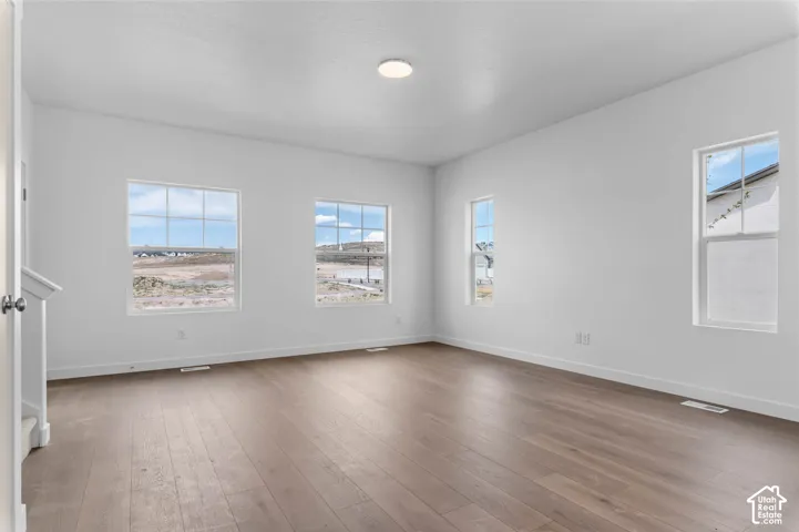 Neutral-toned interior featuring wood-finish flooring, crisp white walls, and four multi-pane windows providing natural light