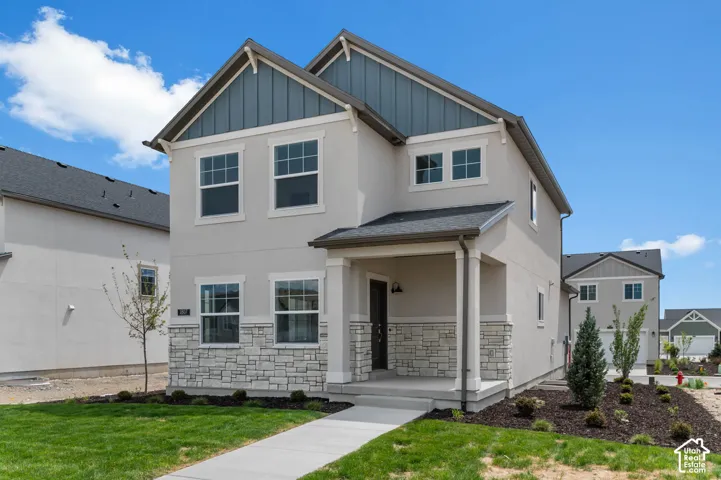 Two-story exterior featuring a mix of stucco and stone veneer siding, vertical board-and-batten gable accents, a covered front porch with square columns, and a concrete walkway