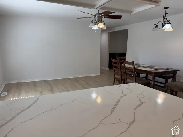 Kitchen featuring a quartz countertop with veining, wood-finish flooring, a coffered ceiling, and two decorative light fixtures