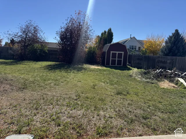 Expansive backyard featuring a detached storage shed, perimeter wood fencing, and mature trees
