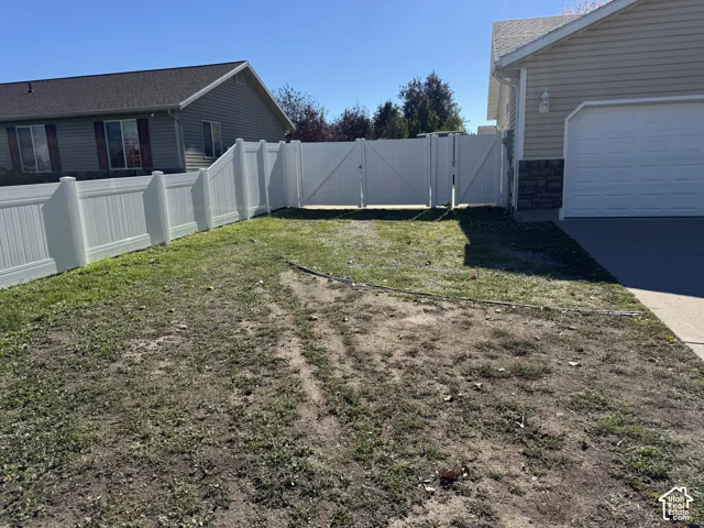 Side yard featuring a white vinyl privacy fence with double-swing gates and a concrete driveway