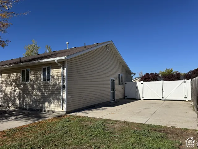 Exterior featuring light-toned horizontal siding, asphalt shingle roof, concrete driveway, and white vinyl privacy fencing