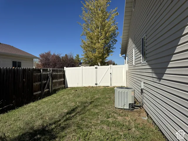 Side yard featuring horizontal vinyl siding, a white vinyl privacy fence with a gated entry, and an exterior HVAC unit