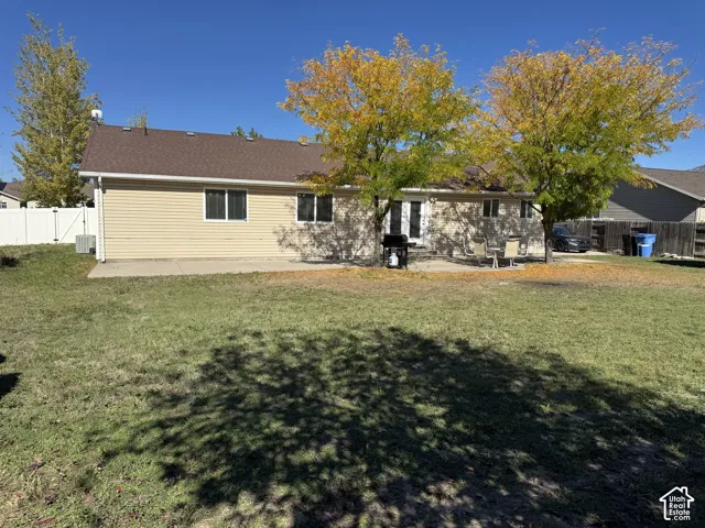 Backyard featuring a concrete patio, vinyl siding, mature trees, and privacy fencing