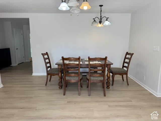 Light-toned wood-finish flooring, two distinct multi-light chandeliers, and neutral wall tones