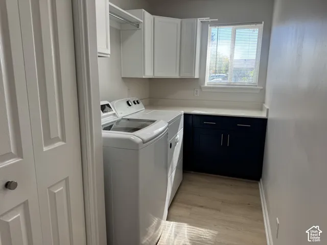 Laundry space featuring white upper cabinetry, deep blue lower cabinets, a solid-surface countertop, and wood-finish flooring