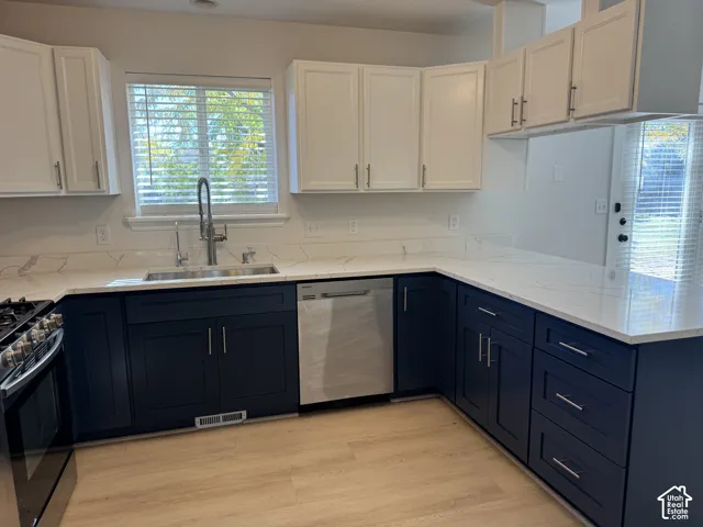 Kitchen featuring dual-tone cabinetry, stone-finish countertops, stainless steel appliances, and a pull-down faucet