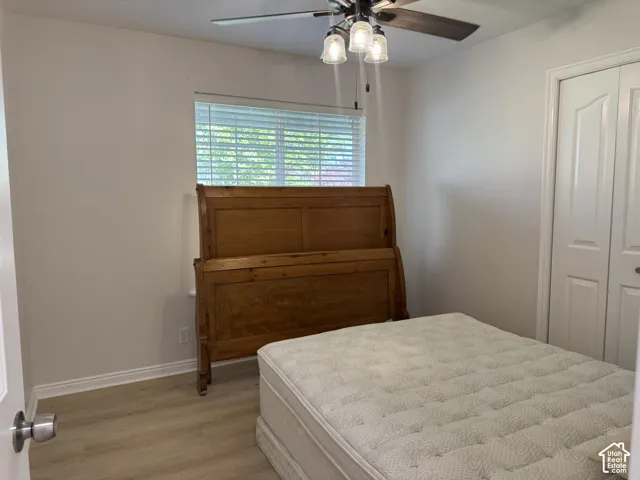 Neutral wall finish, wood-finish flooring, multi-light ceiling fixture with integrated fan, and closet with double-panel doors