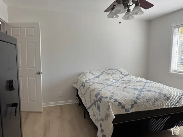 Room featuring wood-finish flooring, a multi-light ceiling fan, and a six-panel door