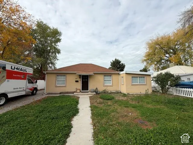 Single-story exterior featuring a hip roof, stucco siding, multi-lite front door, and a concrete walkway
