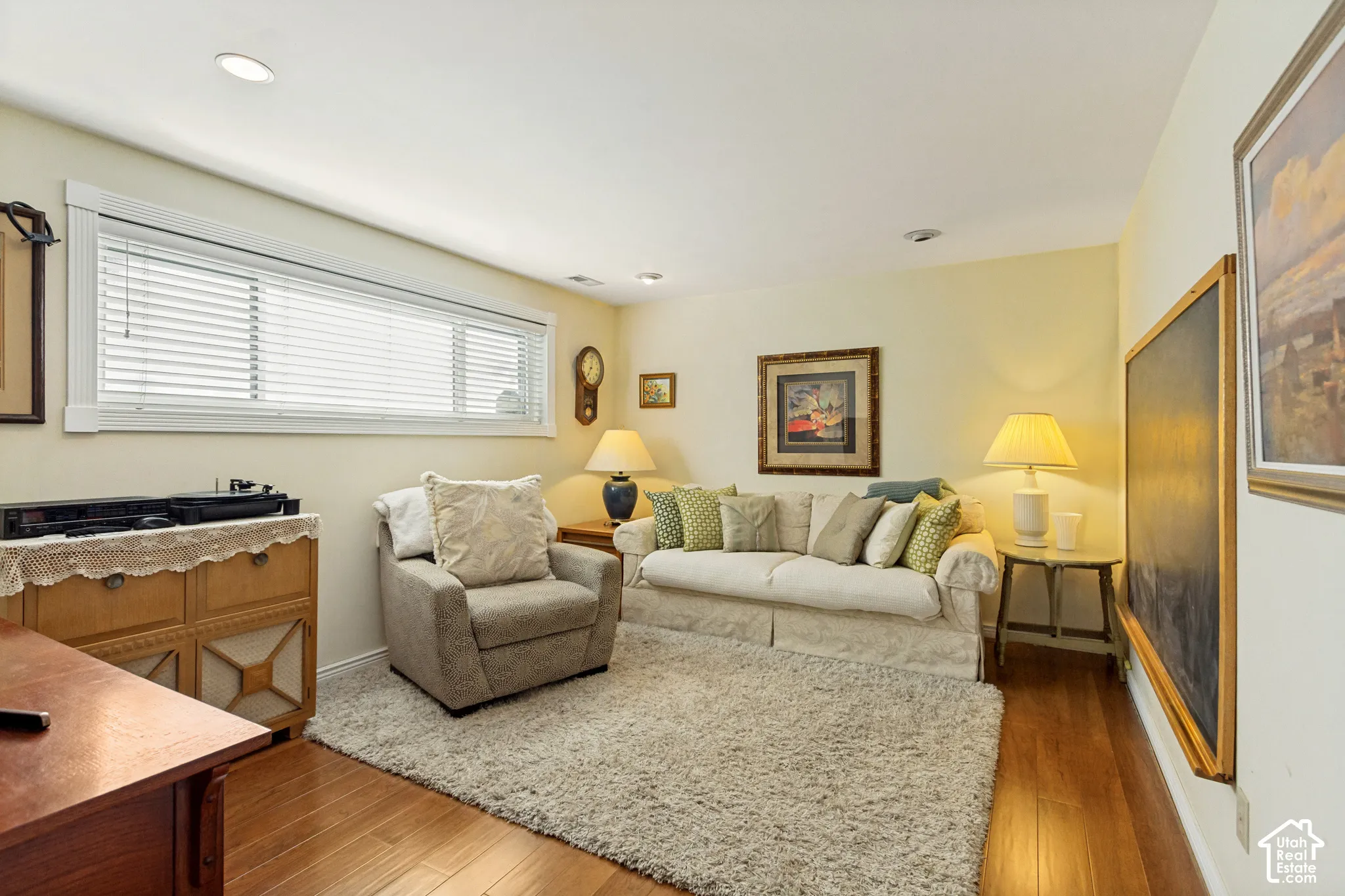 Living space featuring wood-finish flooring, recessed ceiling lighting, and a large horizontal window