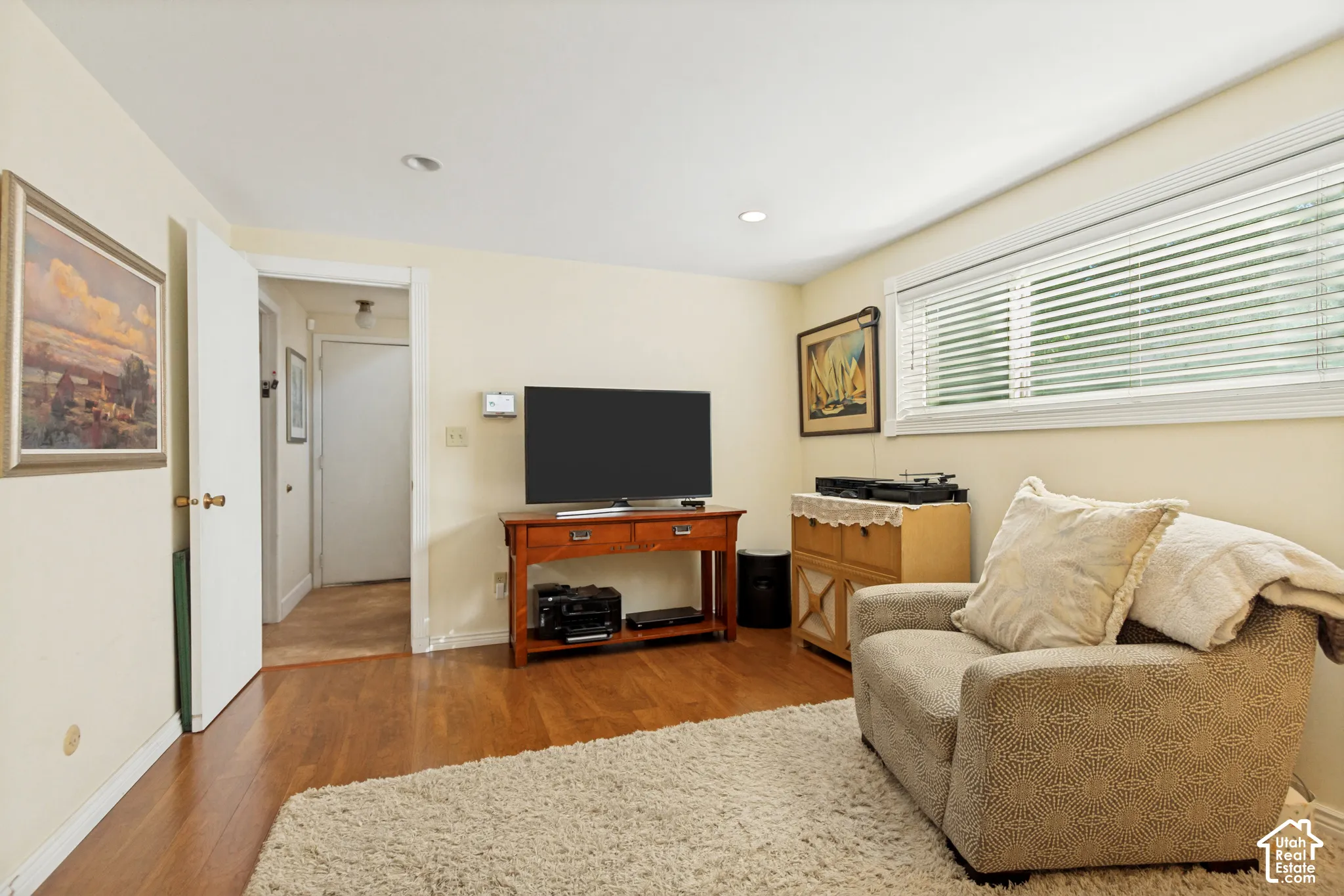 Room featuring wood-finish flooring, recessed lighting, and a large horizontal window with integrated blinds