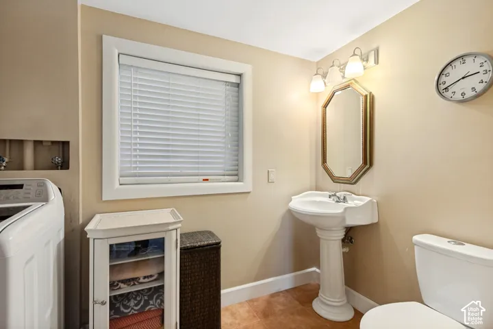Pedestal sink with chrome faucet, octagonal wall mirror, three-light vanity fixture, and tiled flooring