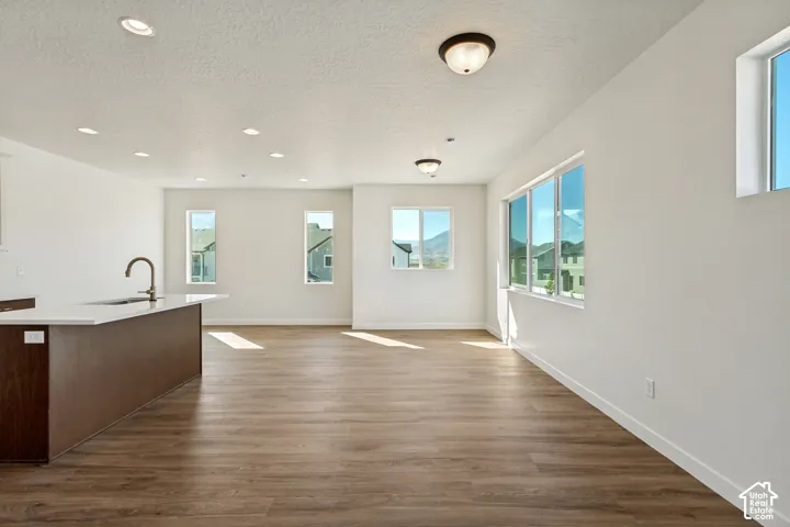Open-concept interior featuring wood-finish flooring, recessed lighting, a kitchen island with stone countertop, and large windows with mountain scenery