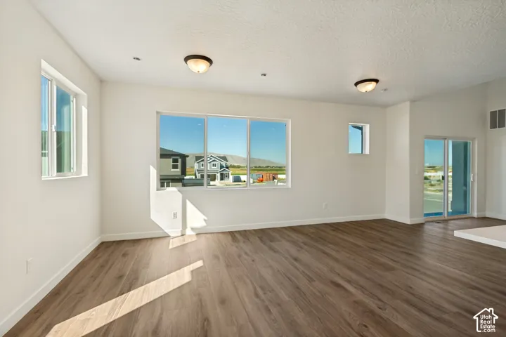 Open-concept interior featuring wood-finish flooring, multi-pane windows, recessed lighting, dual flush-mount light fixtures, and a sliding glass door