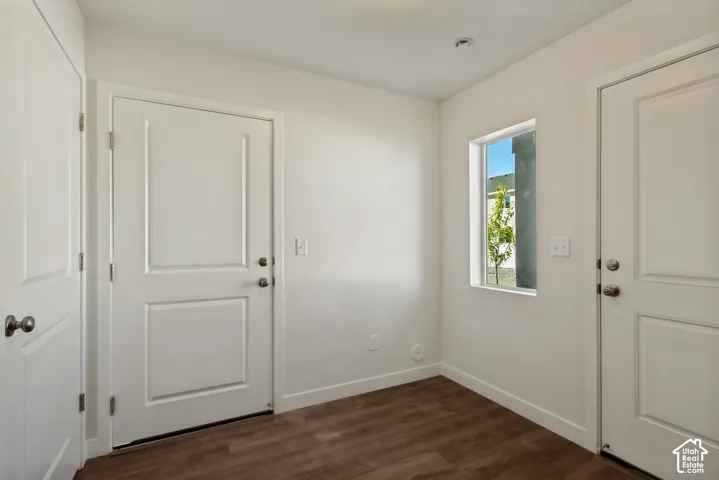 Neutral interior space featuring wood-finish flooring, two white paneled doors with satin nickel hardware, and a single-pane window