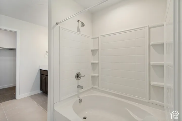 Bathroom featuring a tub and shower combination with integrated shelving, chrome fixtures, dark-finish wood cabinetry, and neutral tile flooring