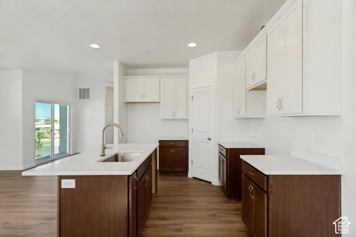 Kitchen featuring a center island, dual-tone cabinetry, light-toned stone countertops, undermount stainless steel sink, and wood-finish flooring