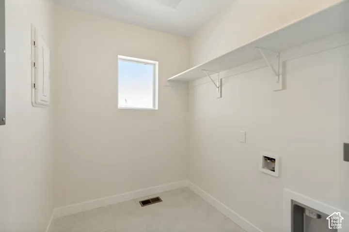 Dedicated utility space featuring neutral-toned tile flooring, built-in shelving, and a natural light-admitting window