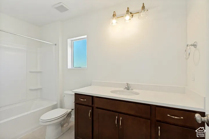 Bathroom featuring a dark wood-finish vanity with a stone-composite countertop, integrated sink, three-light wall fixture, and a white acrylic tub-shower combination
