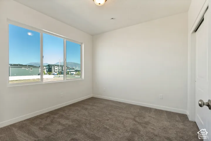 Neutral-toned carpeted flooring, large picture window with mountain scenery, and white interior door with a brushed nickel knob