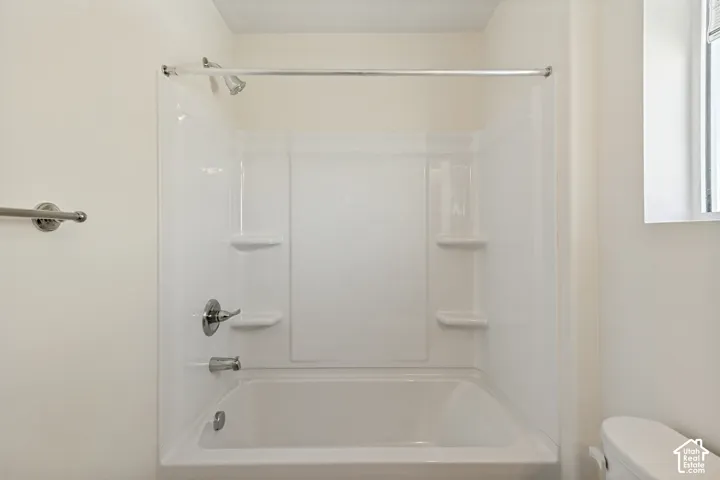 Full-size bathtub featuring a white surround, integrated shelving, a polished metal shower head, and a chrome-finish faucet set