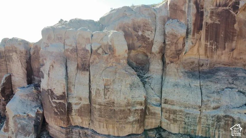 Expansive sandstone rock face featuring natural striations and vertical cleft formations