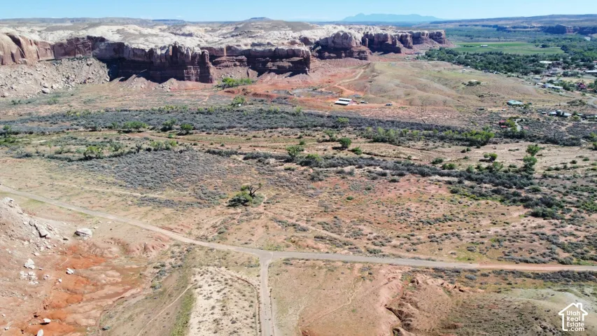 Expansive desert acreage featuring natural rock formations, mesas, mature trees, and existing dirt road access