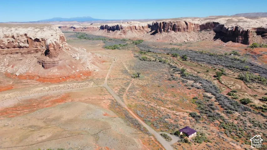 Aerial perspective featuring expansive desert terrain, rock formations, and mountain scenery