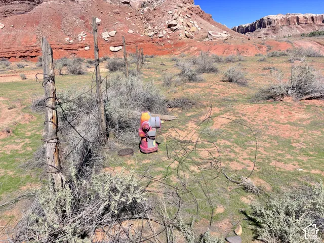 Expansive lot featuring rugged desert terrain, natural stone rock formations, and a rustic wire-strand perimeter fence with weathered wooden posts