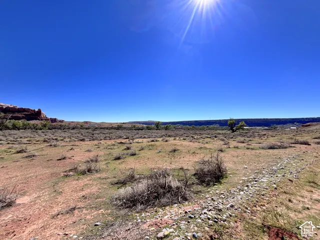 Expansive desert acreage featuring native scrub brush, exposed rock formations, and a stone-lined path