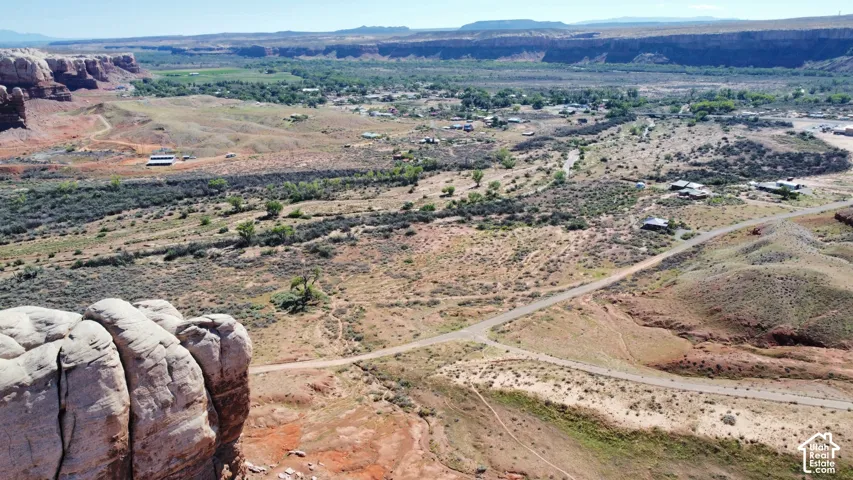 Aerial perspective featuring expansive high-desert terrain, prominent sandstone rock formations, and arid topography
