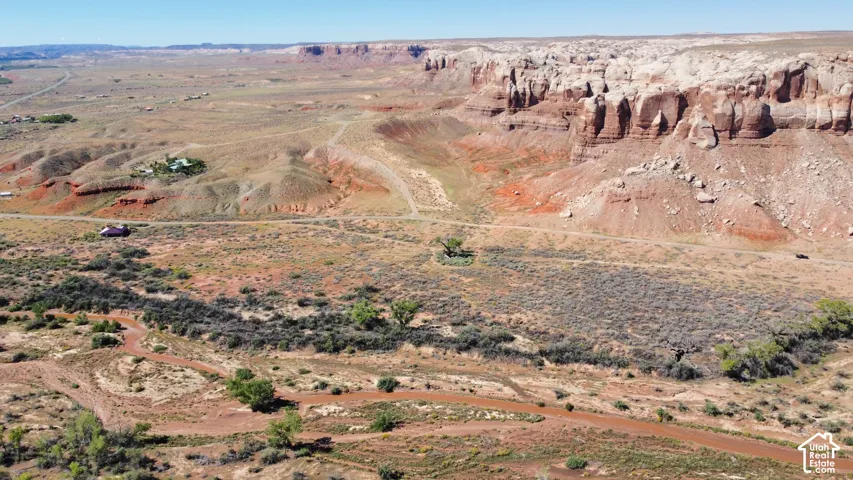 Expansive desert terrain featuring rugged rock formations, native vegetation, natural water drainage, and unpaved access paths