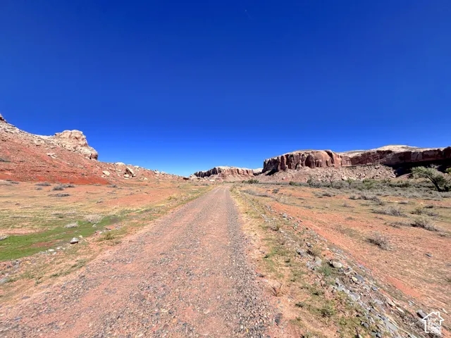 Expansive acreage featuring rugged desert terrain, prominent rock formations, and a gravel access path