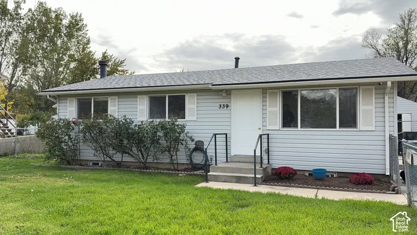 Single-story exterior featuring light gray vinyl siding, white shutter accents, a low-slope roof, and concrete entryway steps with metal handrails