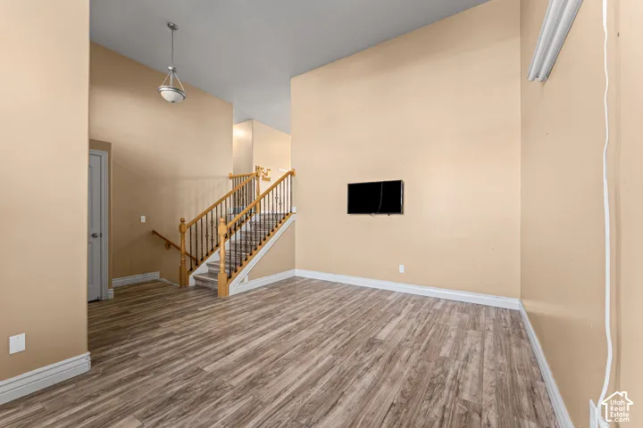 Vaulted ceilings featuring wood-finish flooring, a staircase with metal balusters, and a semi-flush mount pendant light