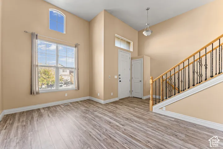 High ceilings featuring an arched window, wood-finish flooring, and a staircase with metal balusters and a wooden handrail