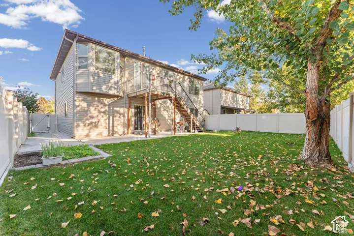 Rear exterior featuring horizontal siding, a raised deck with metal railings, a ground-level concrete patio, and a fully fenced perimeter