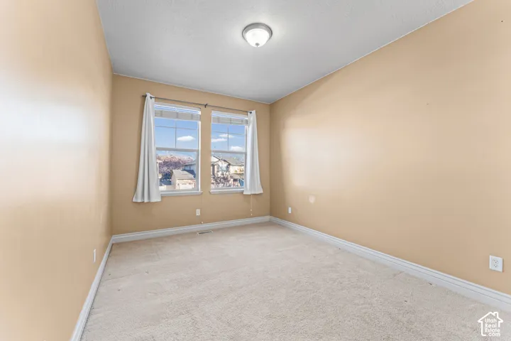 Neutral-toned interior space featuring wall-to-wall carpeting, dual-pane windows, and a flush-mount ceiling light fixture