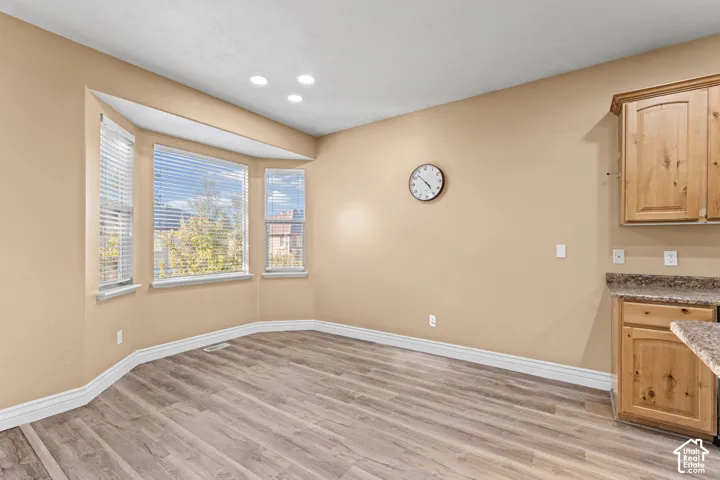 Bay window with three-panel glazing, wood-finish flooring, and recessed ceiling lighting