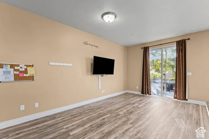 Room featuring wood-finish flooring, a neutral wall palette, flush-mount ceiling lighting, and sliding glass doors with exterior access