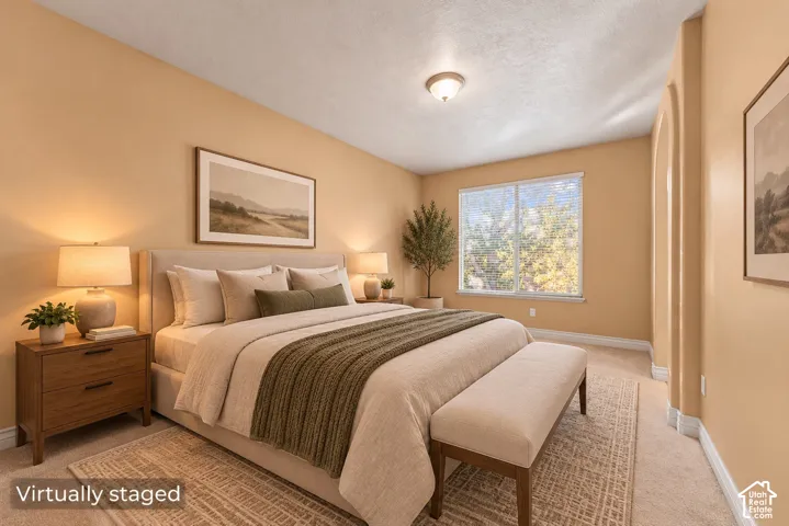 Bedroom featuring neutral wall paint, carpeted flooring, a large window, and an arched doorway